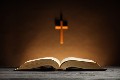 Photo of Bible and cross on brown wall, selective focus. Religion of Christianity