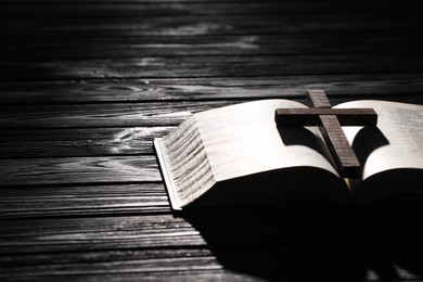 Photo of Bible and cross on black wooden table, space for text. Religion of Christianity