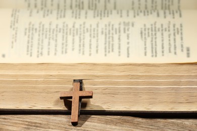 Photo of Bible and cross on wooden table, closeup. Religion of Christianity
