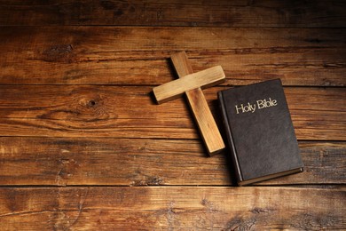 Bible and cross on wooden table, flat lay with space for text. Religion of Christianity