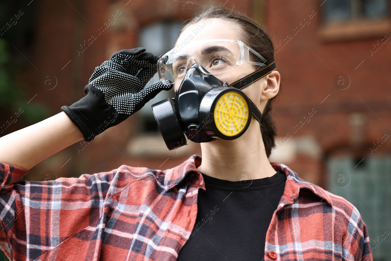 Photo of Woman in respirator and protective glasses outdoors