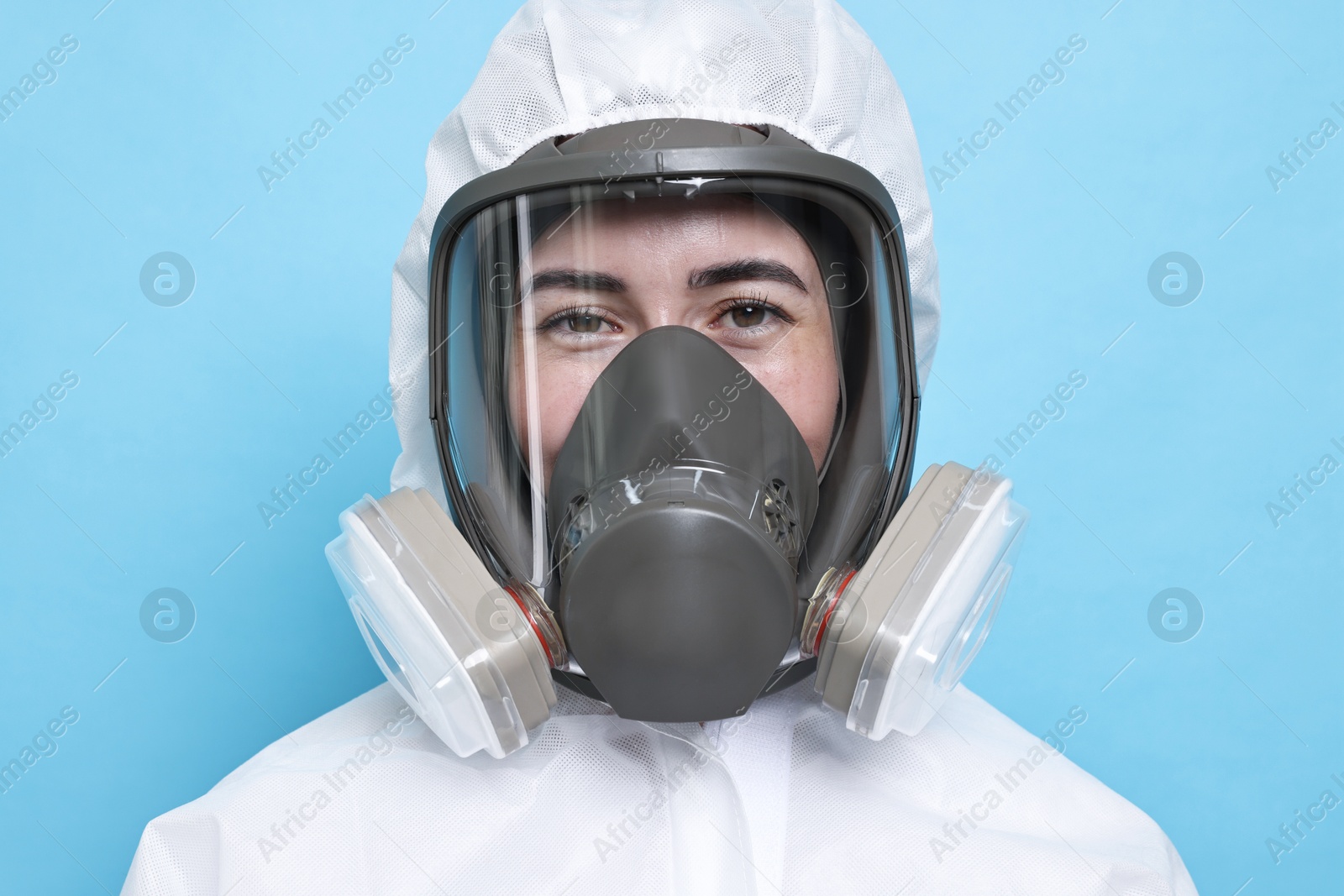 Photo of Worker in respirator and protective suit on light blue background