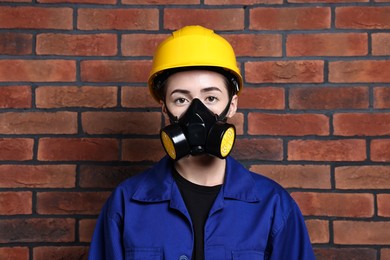 Worker in respirator and helmet near brick wall