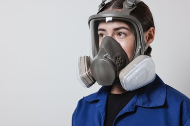 Worker in respirator on grey background, space for text