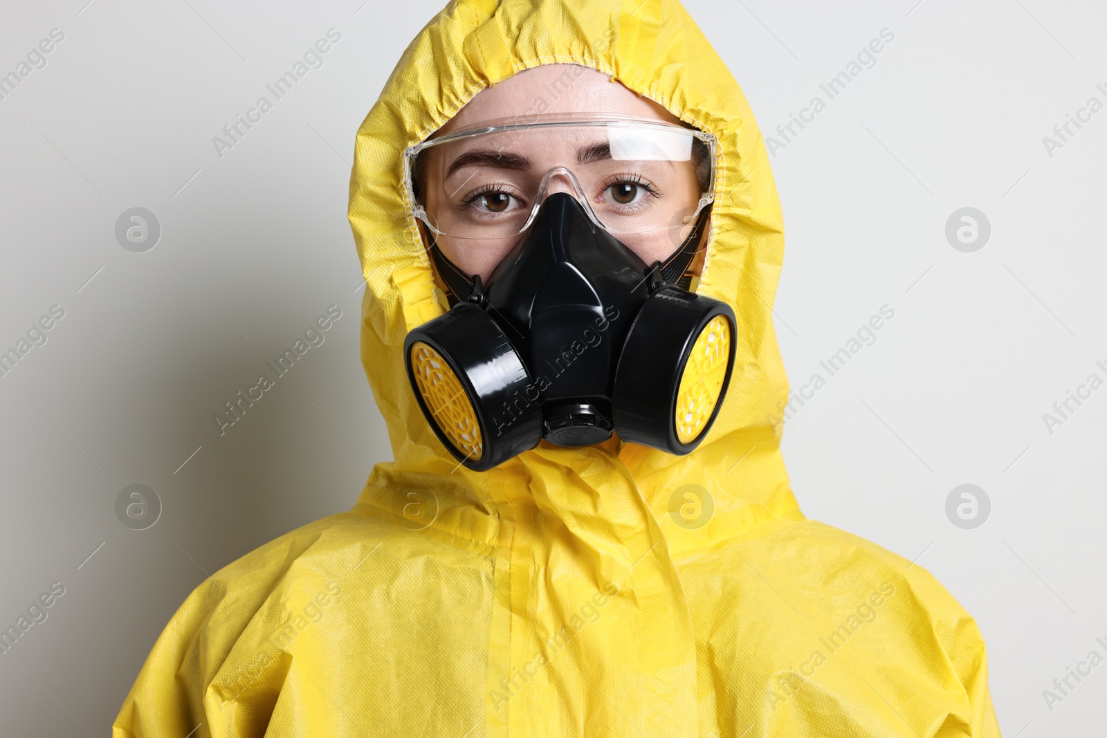 Photo of Worker in respirator, protective suit and glasses on grey background