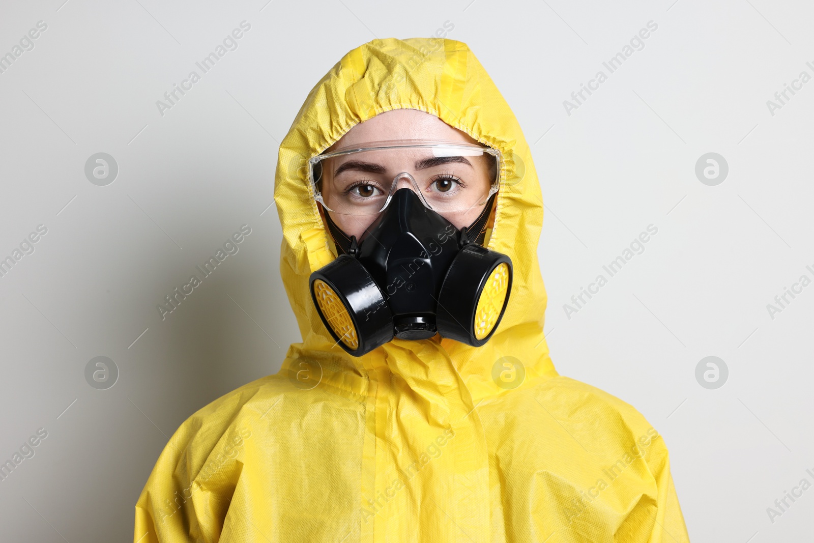 Photo of Worker in respirator, protective suit and glasses on grey background