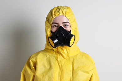 Worker in respirator and protective suit on grey background
