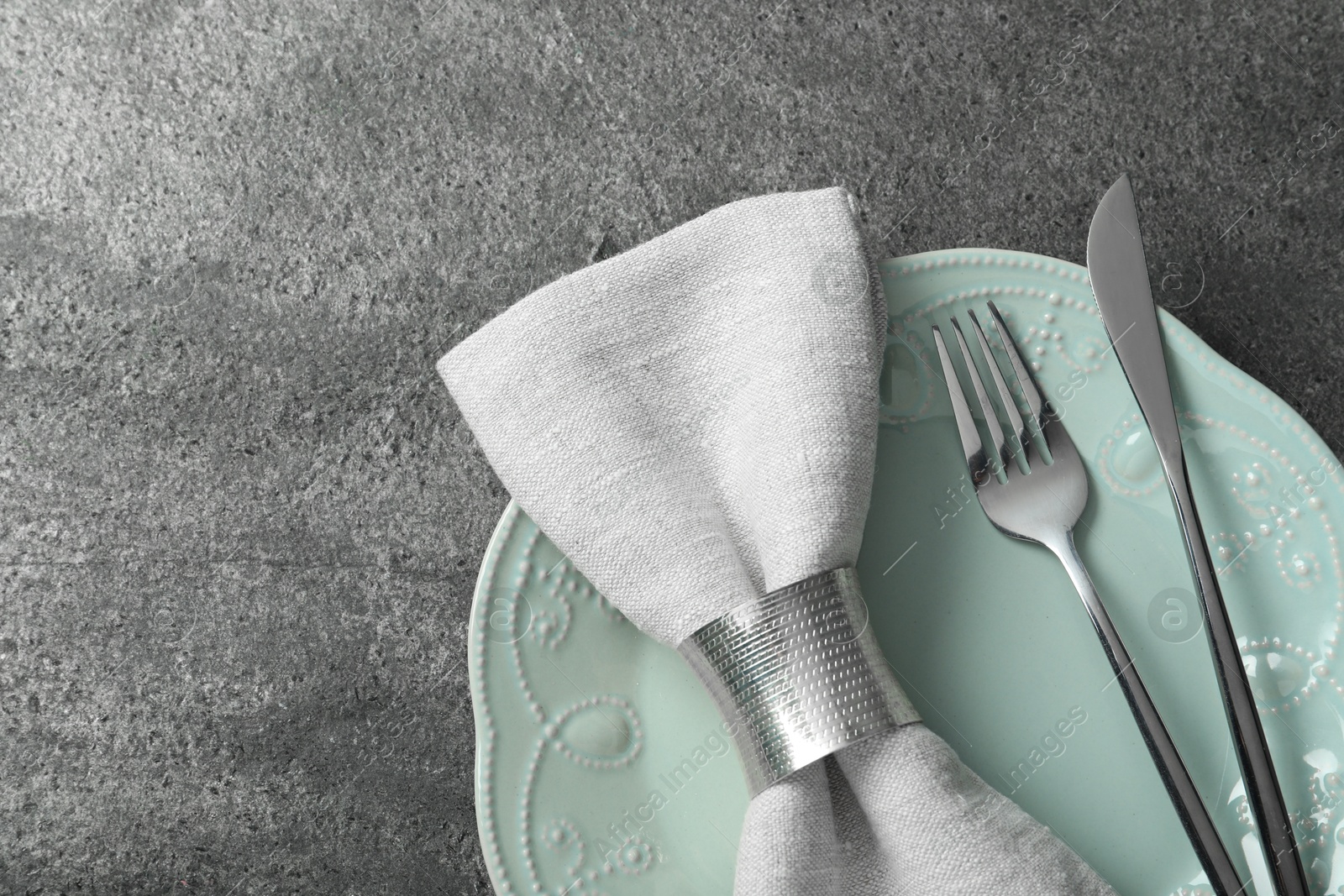 Photo of Stylish silver cutlery, plate and napkin on grey table, top view. Space for text