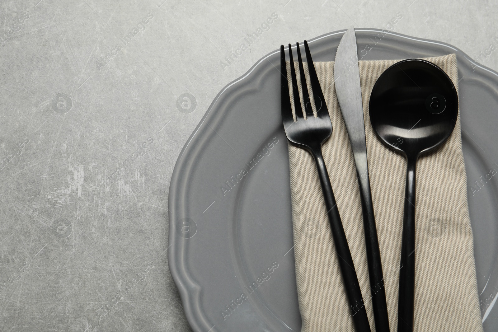 Photo of Stylish cutlery, napkin and plate on grey table, top view. Space for text