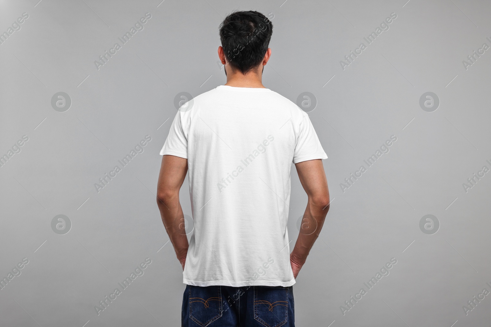 Photo of Man in white t-shirt on grey background, back view