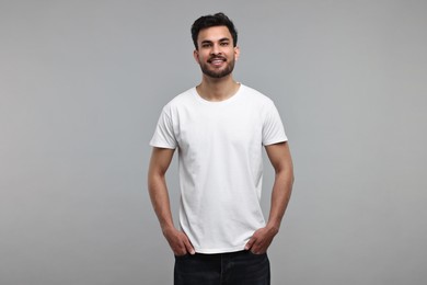 Photo of Smiling man in white t-shirt on grey background