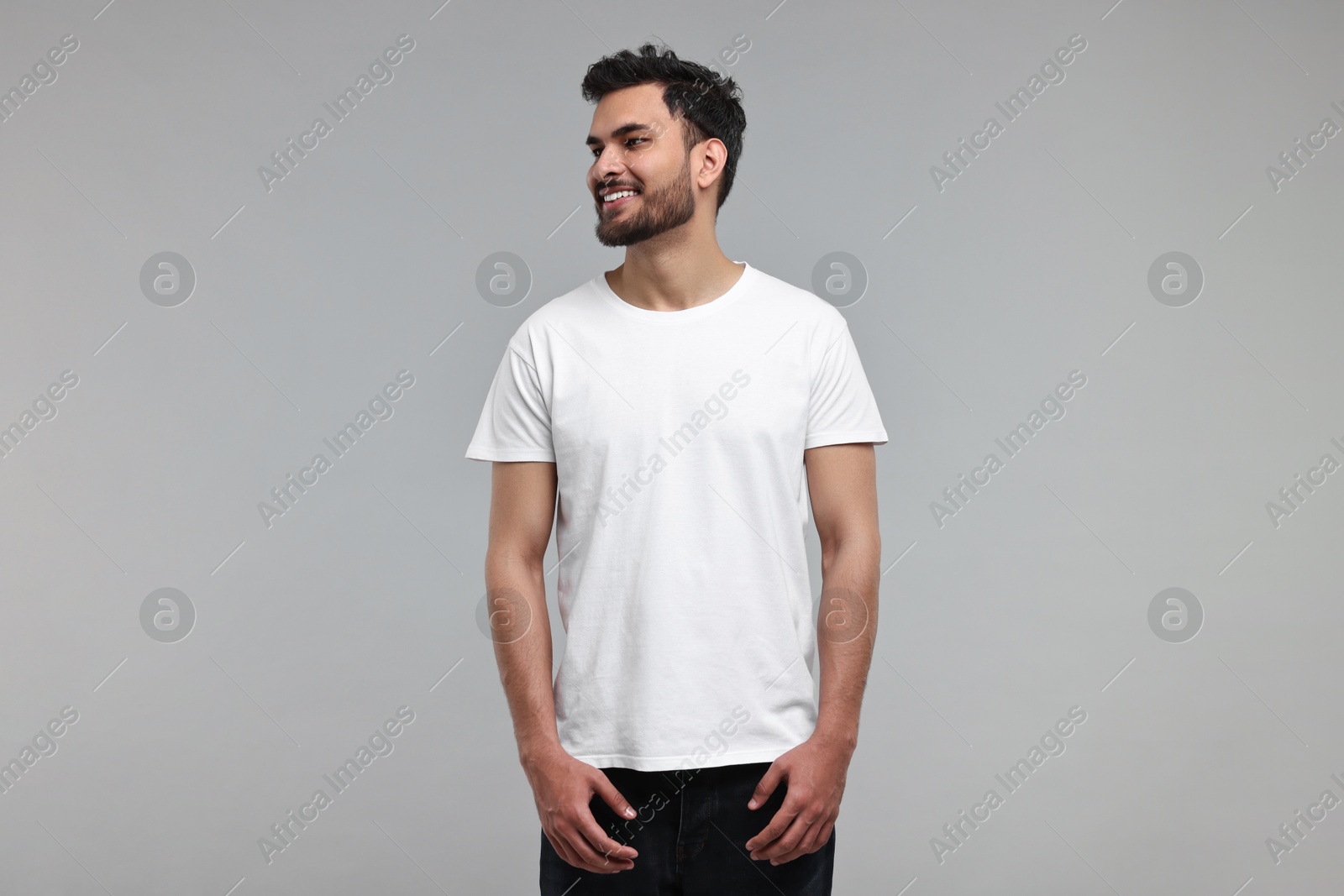 Photo of Smiling man in white t-shirt on grey background