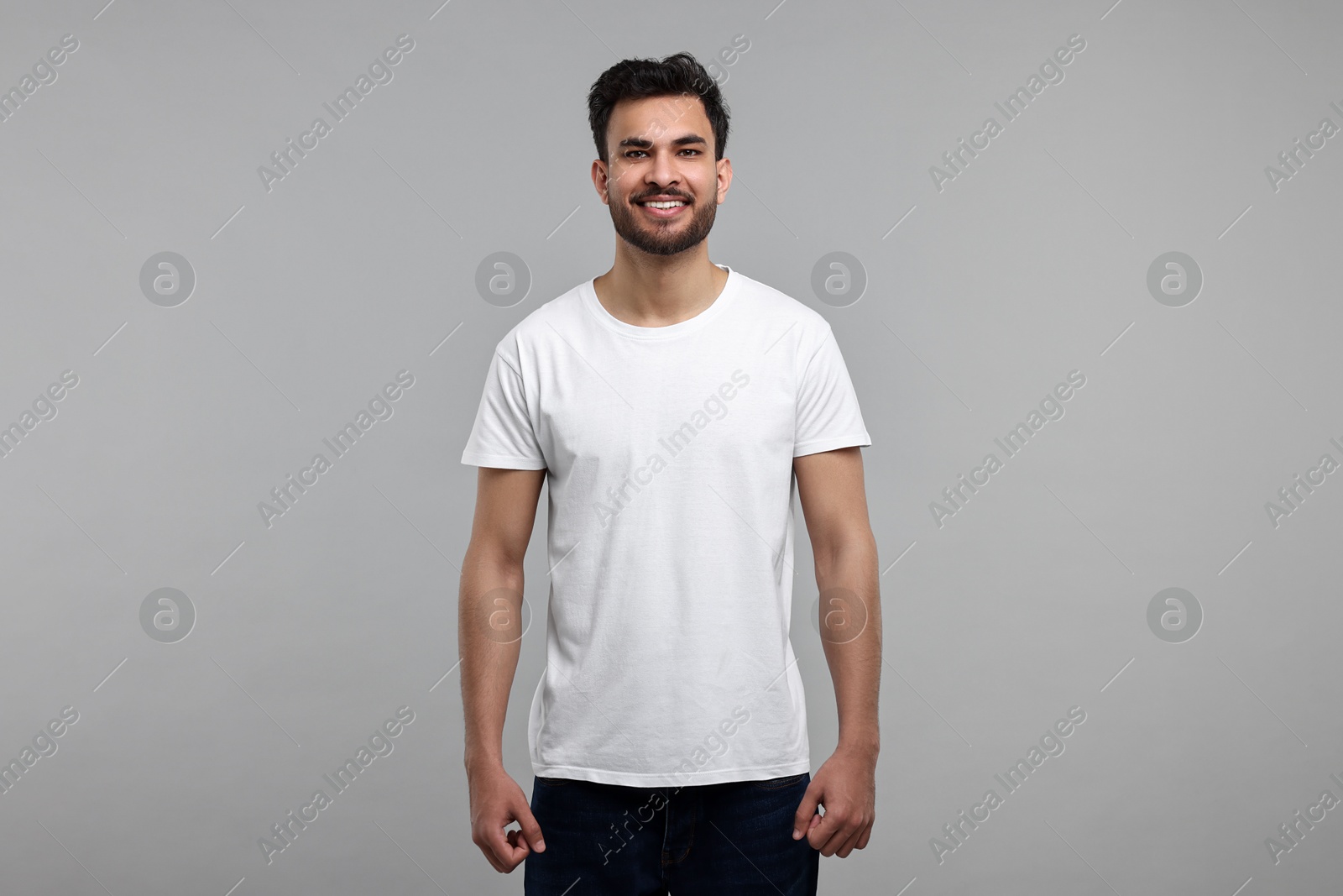 Photo of Smiling man in white t-shirt on grey background