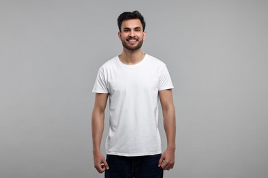 Photo of Smiling man in white t-shirt on grey background