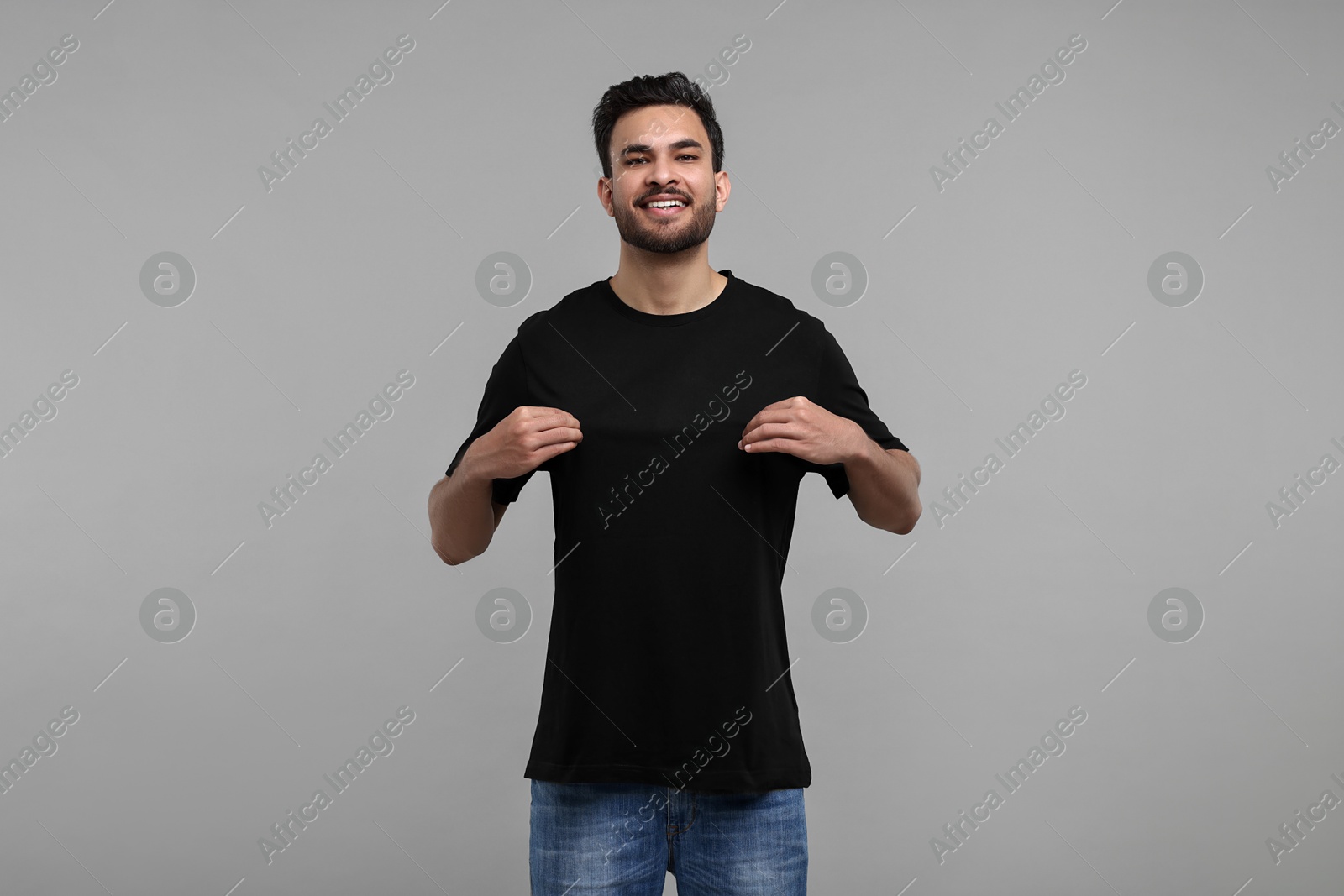 Photo of Smiling man in black t-shirt on grey background