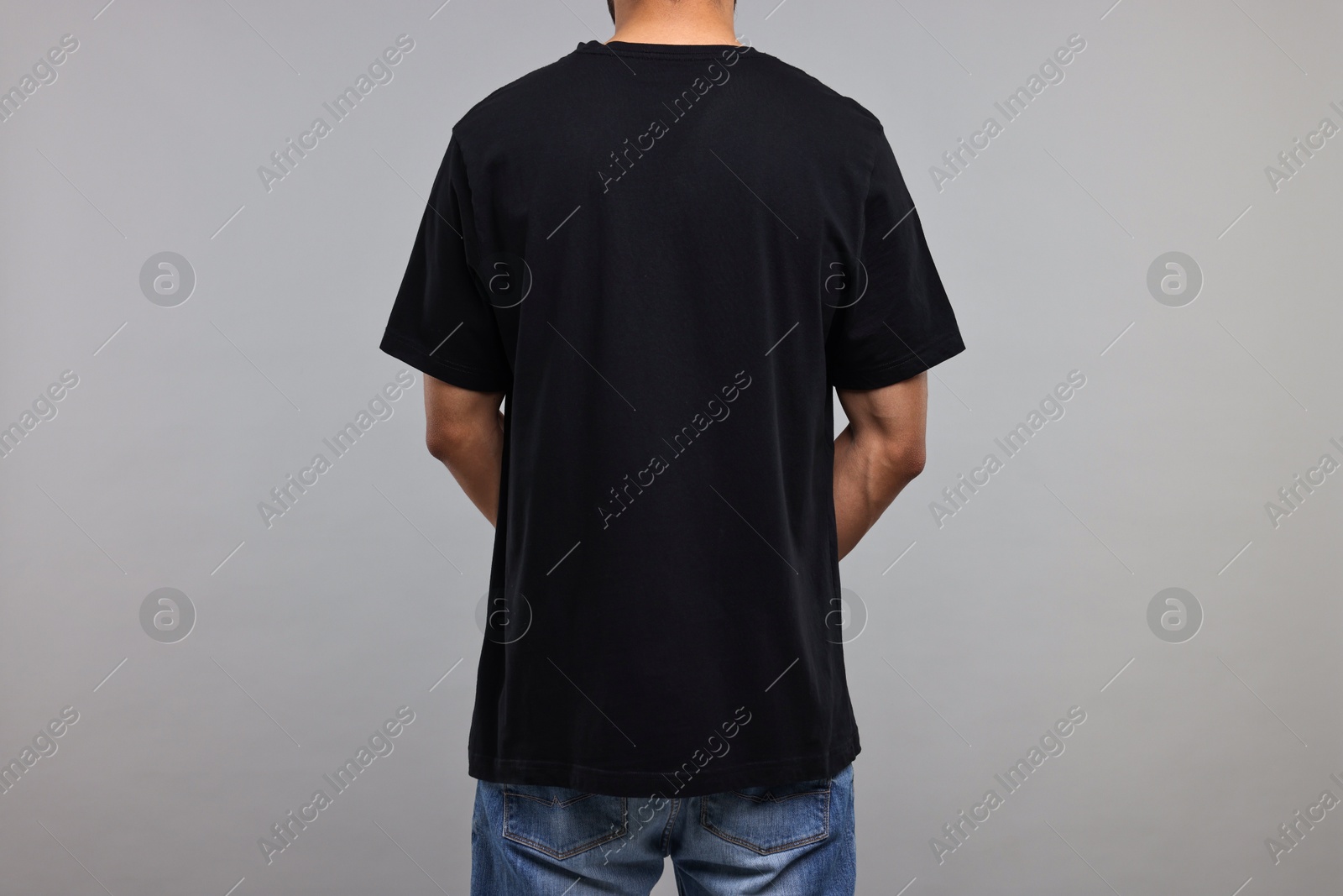 Photo of Man in black t-shirt on grey background, back view