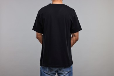 Photo of Man in black t-shirt on grey background, back view