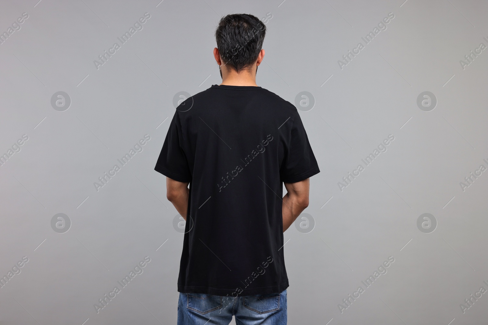 Photo of Man in black t-shirt on grey background, back view