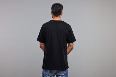 Photo of Man in black t-shirt on grey background, back view