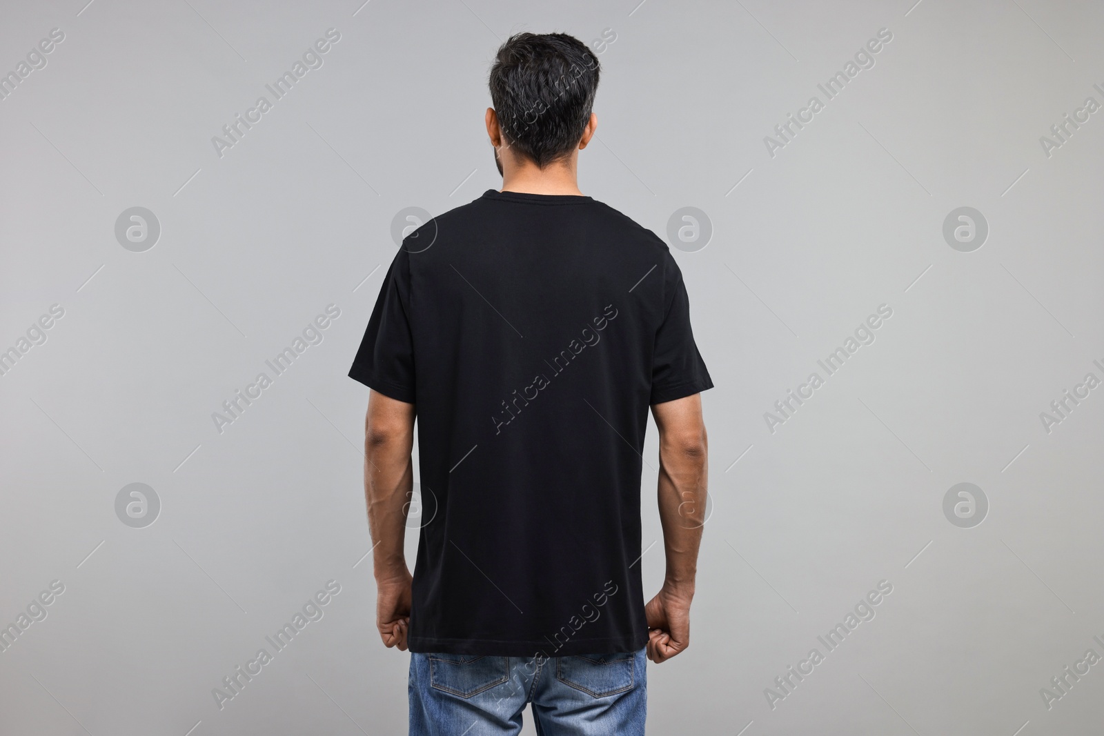 Photo of Man in black t-shirt on grey background, back view