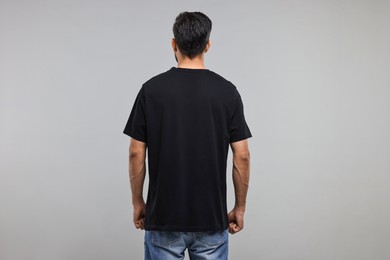 Photo of Man in black t-shirt on grey background, back view