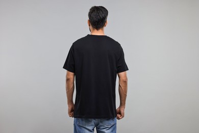 Man in black t-shirt on grey background, back view