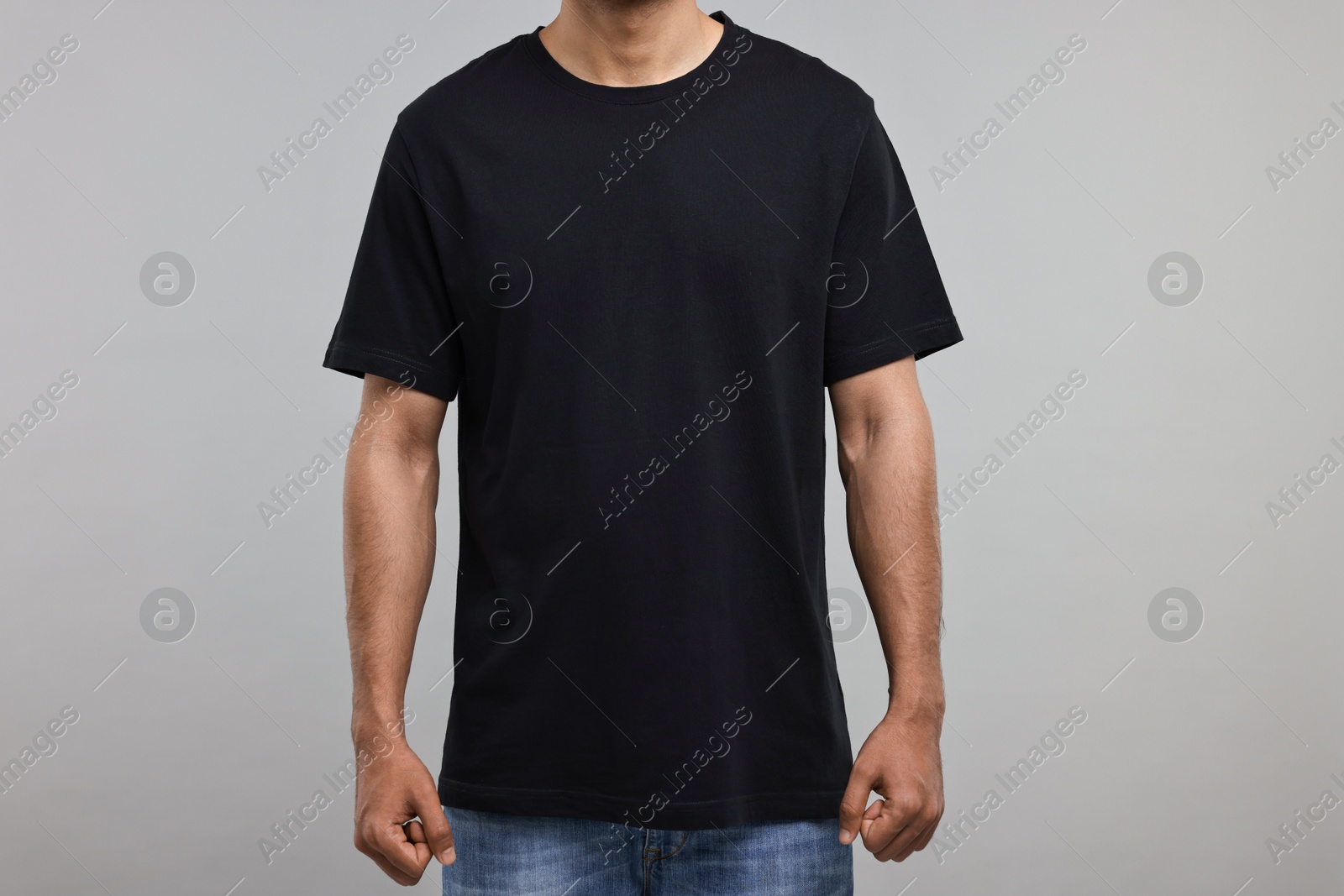 Photo of Man in black t-shirt on grey background, closeup