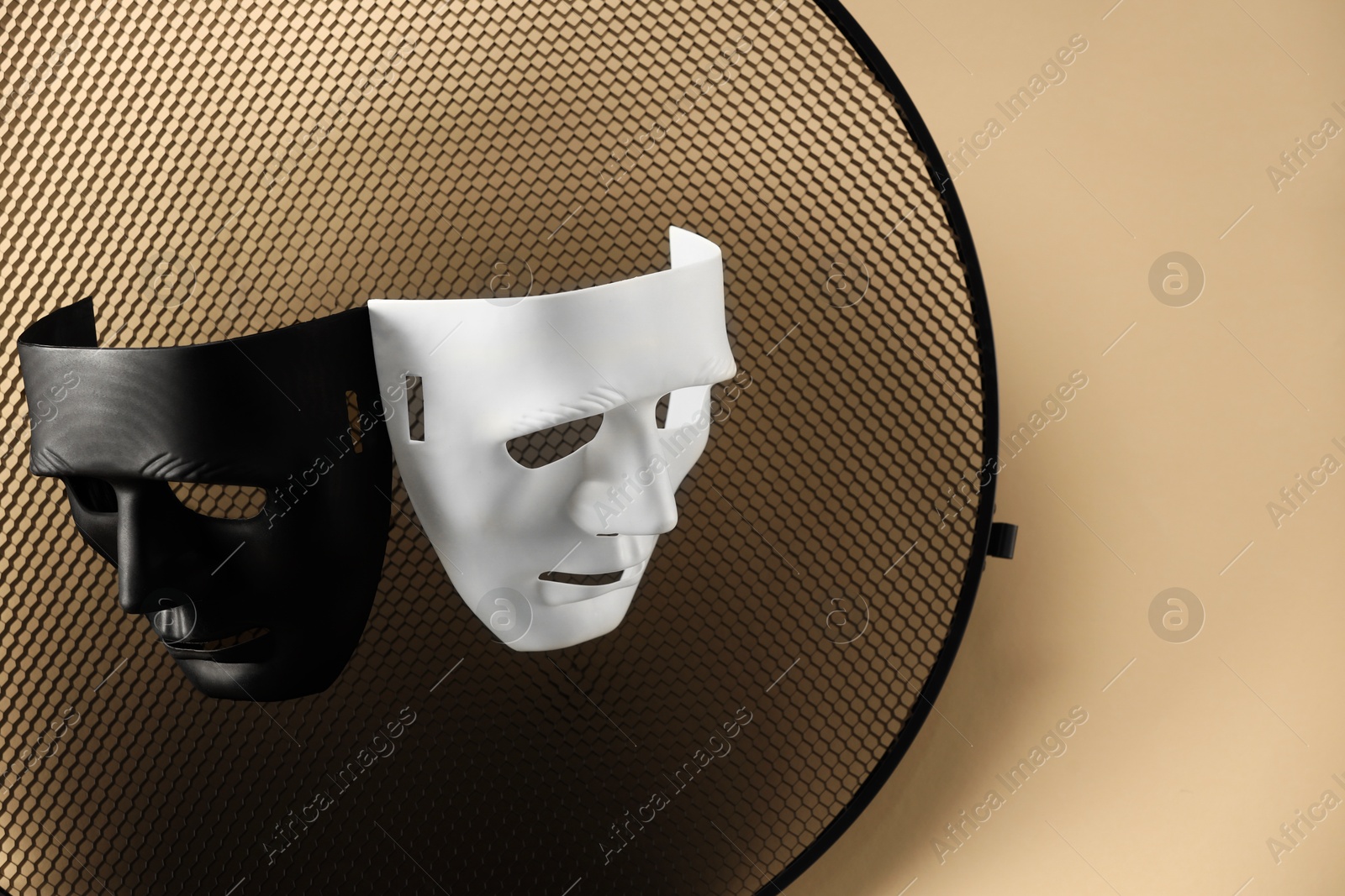 Photo of Theater arts. Two masks and honeycomb grid on beige background, top view. Space for text