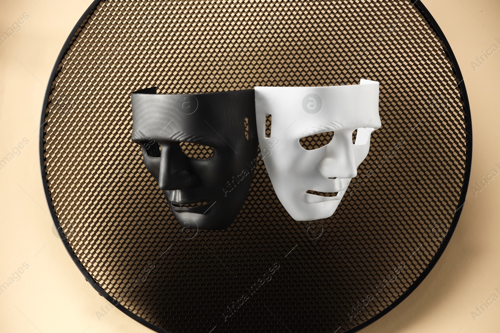 Photo of Theater arts. Two masks and honeycomb grid on beige background, top view