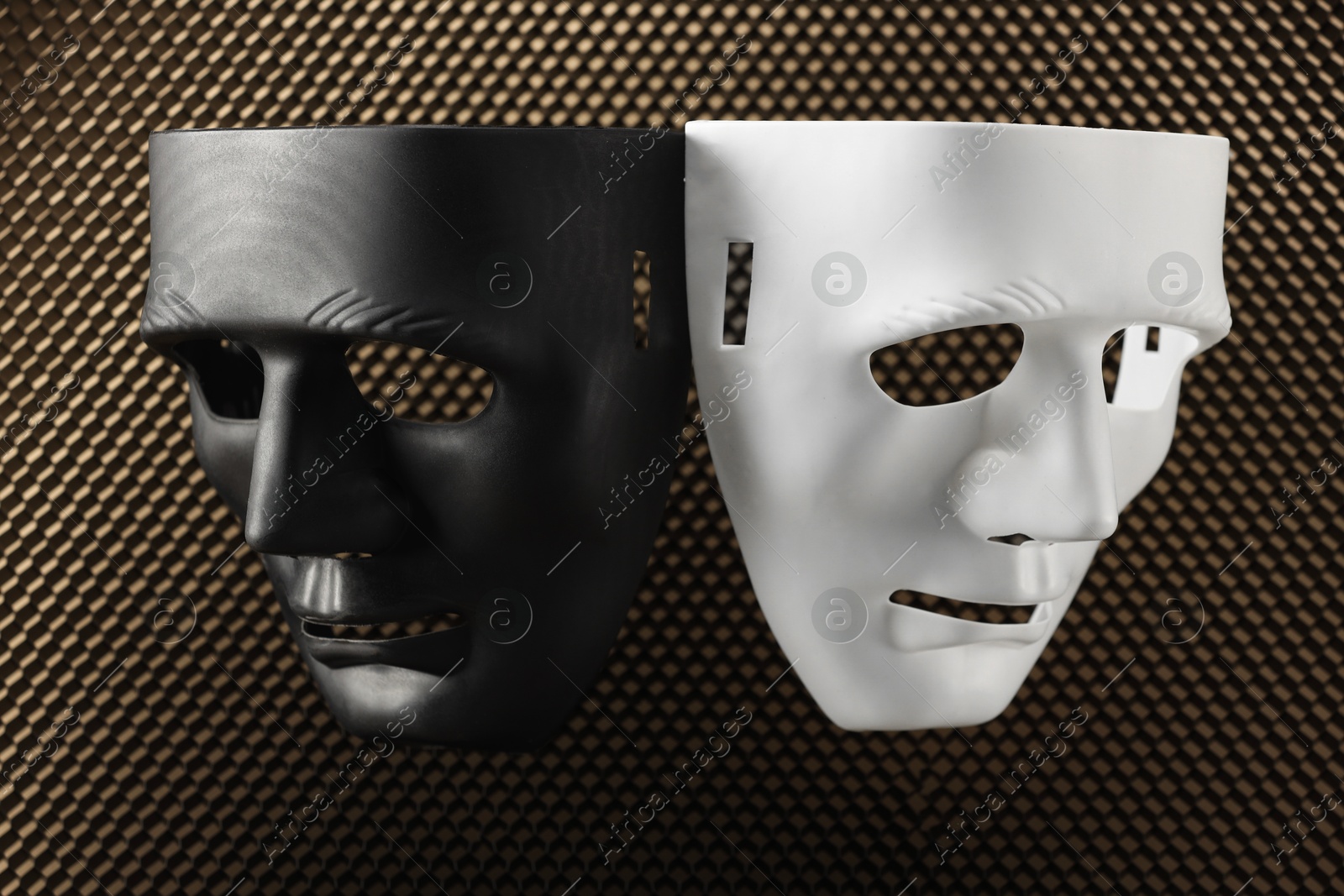 Photo of Theater arts. Black and white masks on honeycomb grid, top view