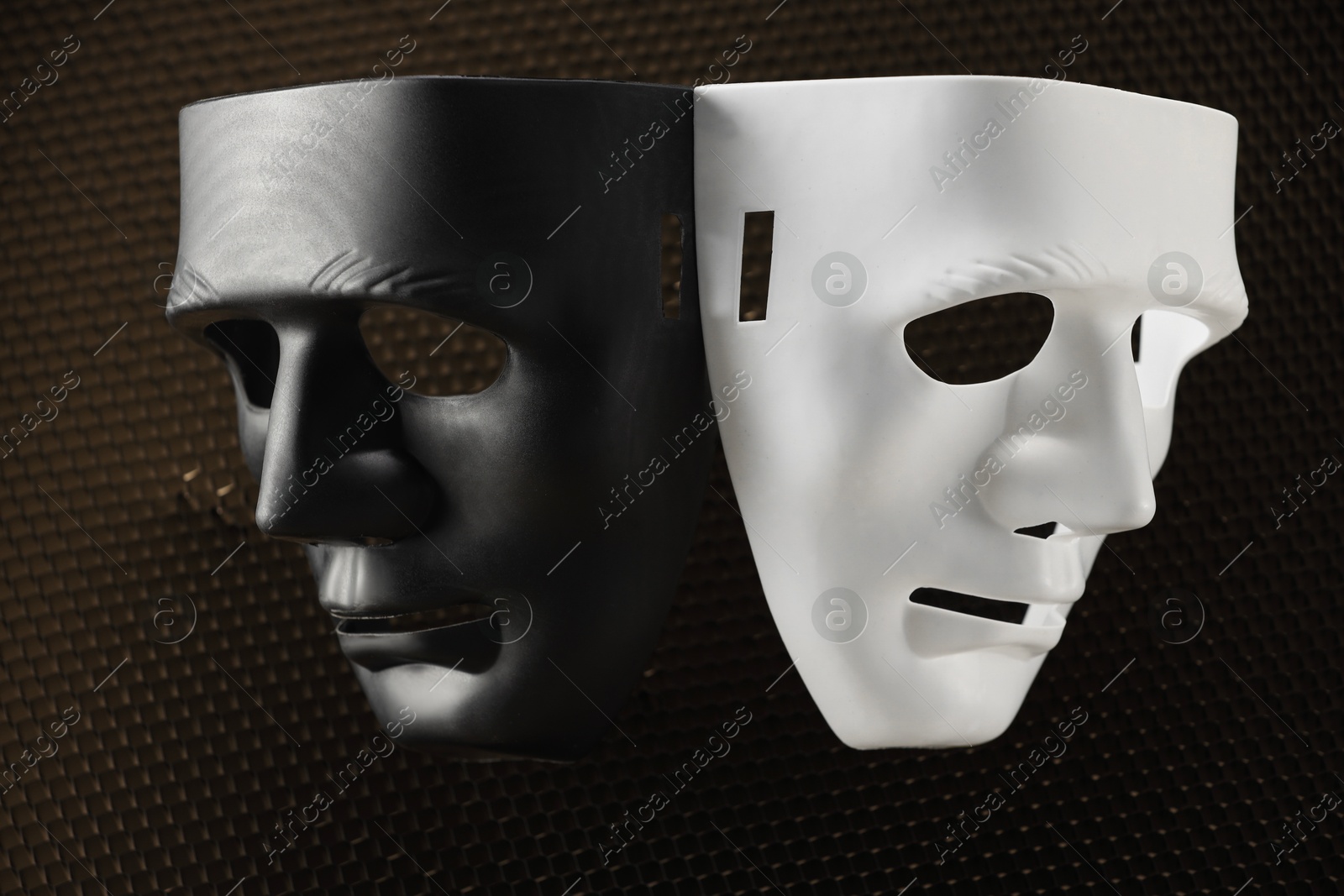 Photo of Theater arts. Black and white masks on honeycomb grid, top view