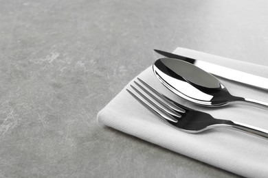 Photo of Stylish cutlery set and napkin on grey table. Space for text