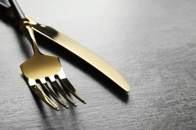 Stylish cutlery. Golden knife and fork on grey table, closeup. Space for text