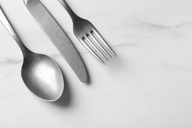 Photo of Stylish silver cutlery set on white marble table, flat lay. Space for text