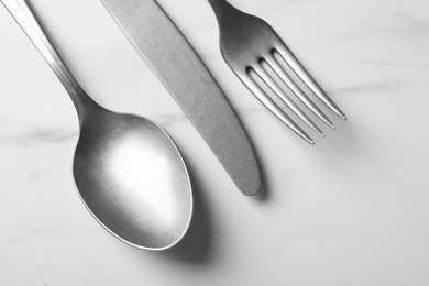 Photo of Stylish silver cutlery set on white marble table, flat lay