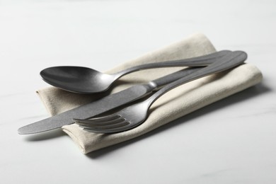 Photo of Stylish cutlery set and napkin on white table