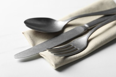 Stylish cutlery set and napkin on white table, closeup