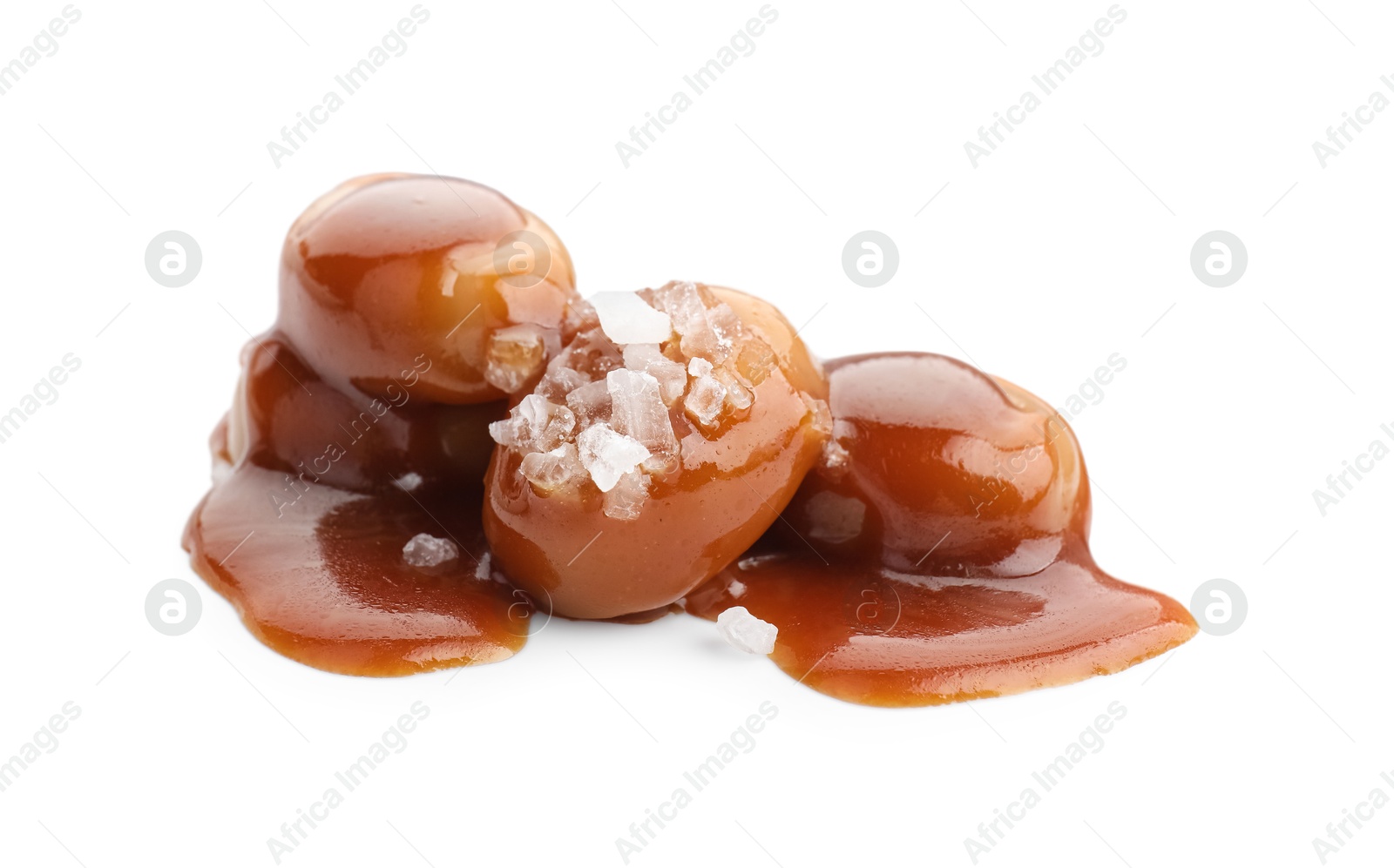 Photo of Yummy candies with caramel sauce and sea salt isolated on white