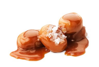 Photo of Yummy candies with caramel sauce and sea salt isolated on white