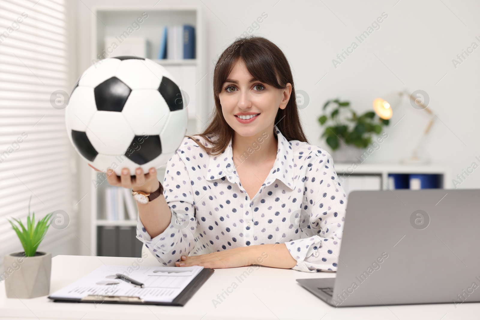 Photo of Smiling employee with soccer ball at table in office