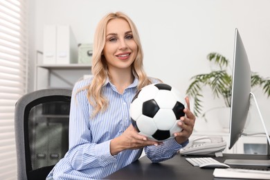 Photo of Happy woman with soccer ball at table in office