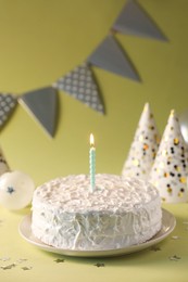 Photo of Tasty cake with burning candle on green background