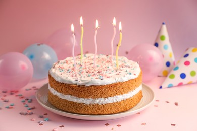 Photo of Tasty cake with colorful candles on pink background, closeup