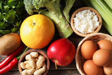 Photo of Healthy meal. Different vegetables and raw eggs on wooden table, flat lay