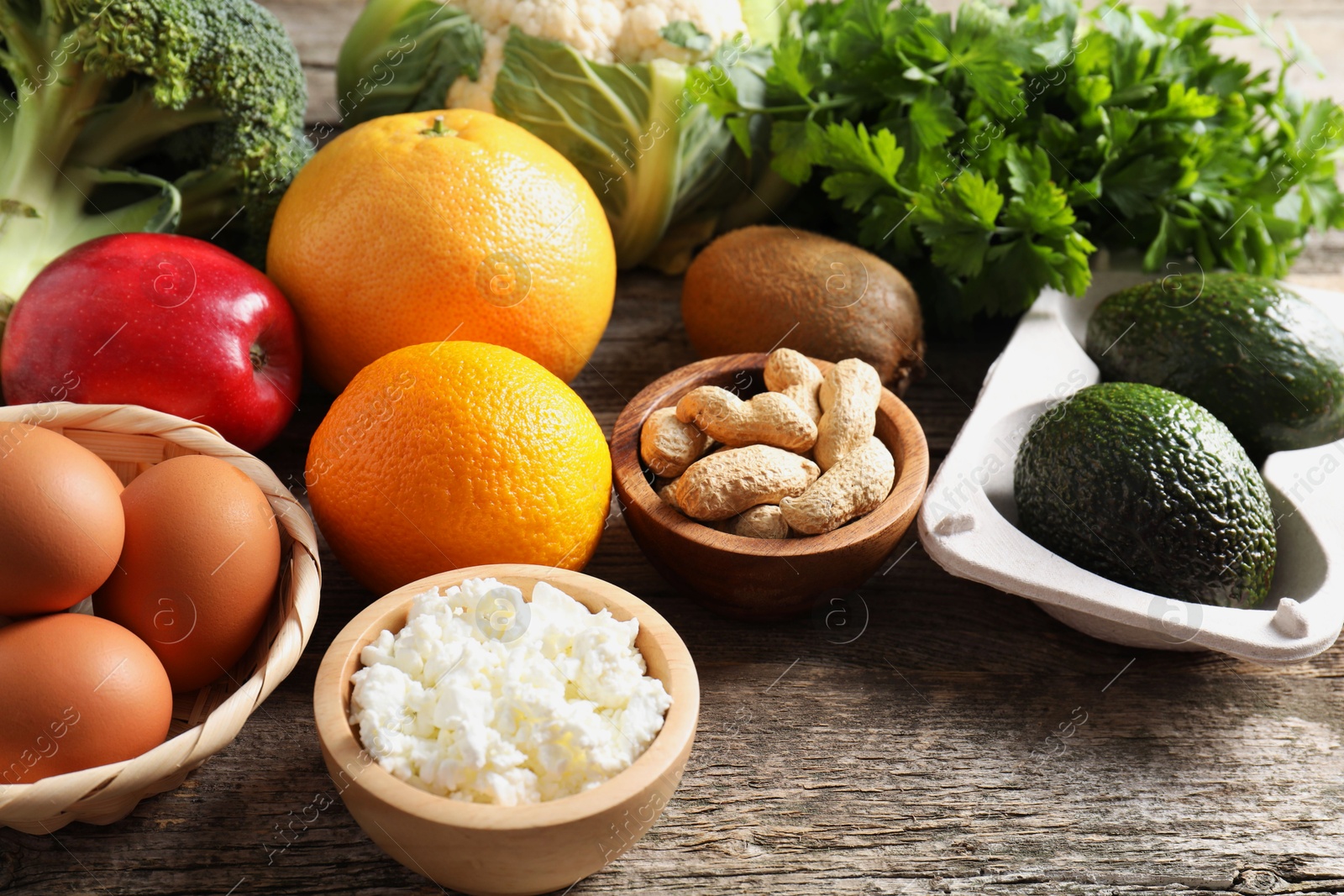 Photo of Healthy meal. Different vegetables and raw eggs on wooden table, closeup