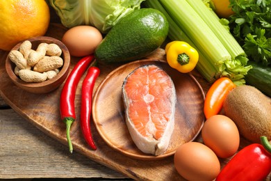 Photo of Healthy meal. Different vegetables and raw salmon on wooden table