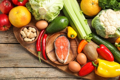 Photo of Healthy meal. Different vegetables and raw salmon on wooden table, flat lay