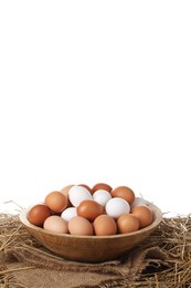 Photo of Fresh chicken eggs in bowl and dried straw on table against white background