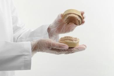 Photo of Doctor holding dental model with jaws on white background, closeup. Cast of teeth