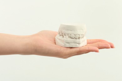 Woman holding dental model with jaws on white background, closeup. Cast of teeth